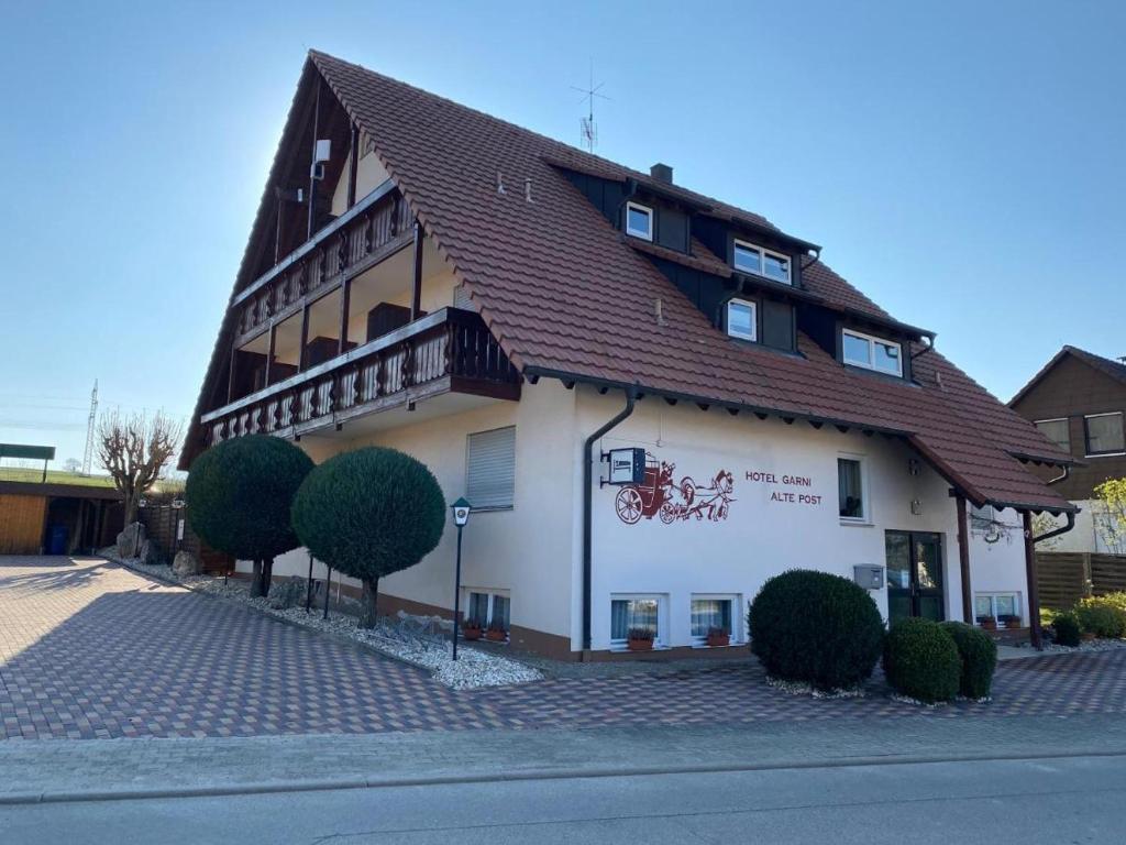 een groot wit gebouw met een bruin dak bij Hotel Garni Alte Post in Schallbach