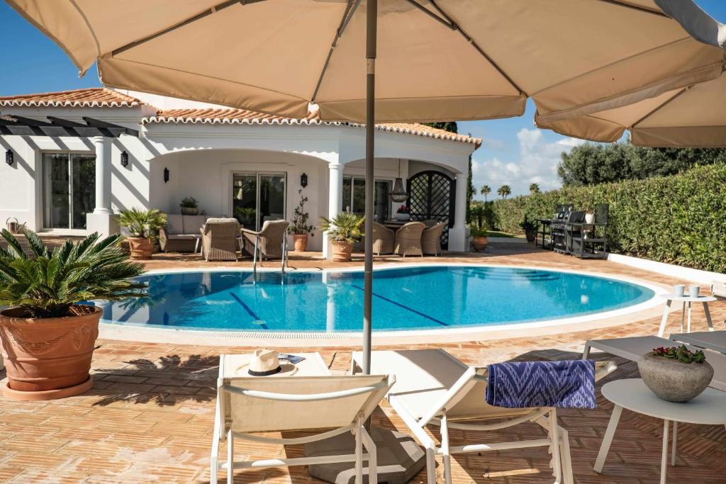 een zwembad met stoelen en een parasol bij Casa Rosella in Carvoeiro