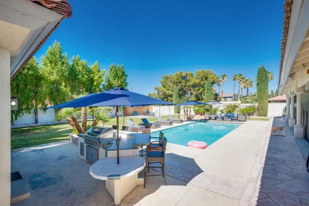 a swimming pool with an umbrella and a grill at Luxury Vegas Home with 5BR, Casita, Hot Tub, and Pool in Las Vegas