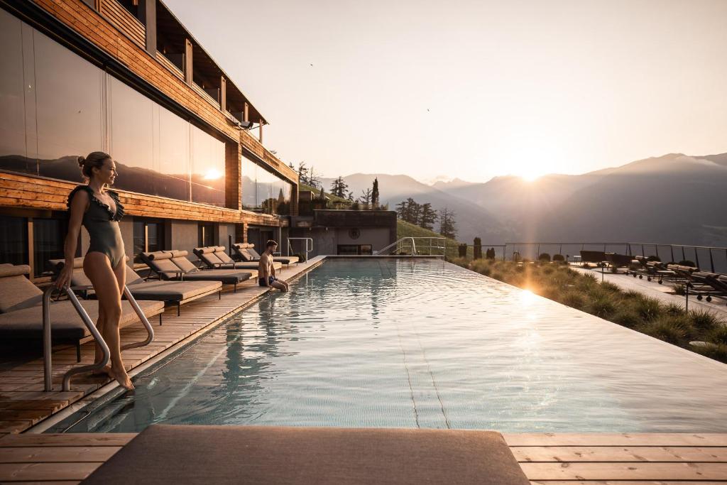 eine Frau, die am Rande eines Pools in einem Hotel steht in der Unterkunft DAS GERSTL Alpine Retreat in Mals im Vinschgau