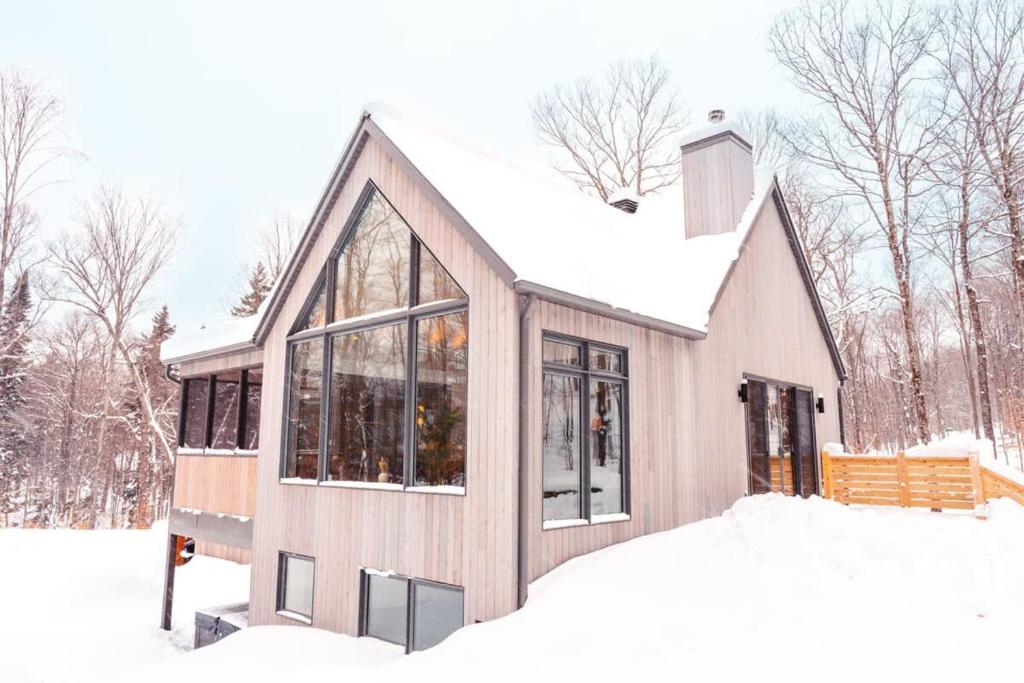 a house covered in snow in the woods at Le coup de coeur du Lac Supérieur - 3 minutes from Tremblant! in Lac-Superieur