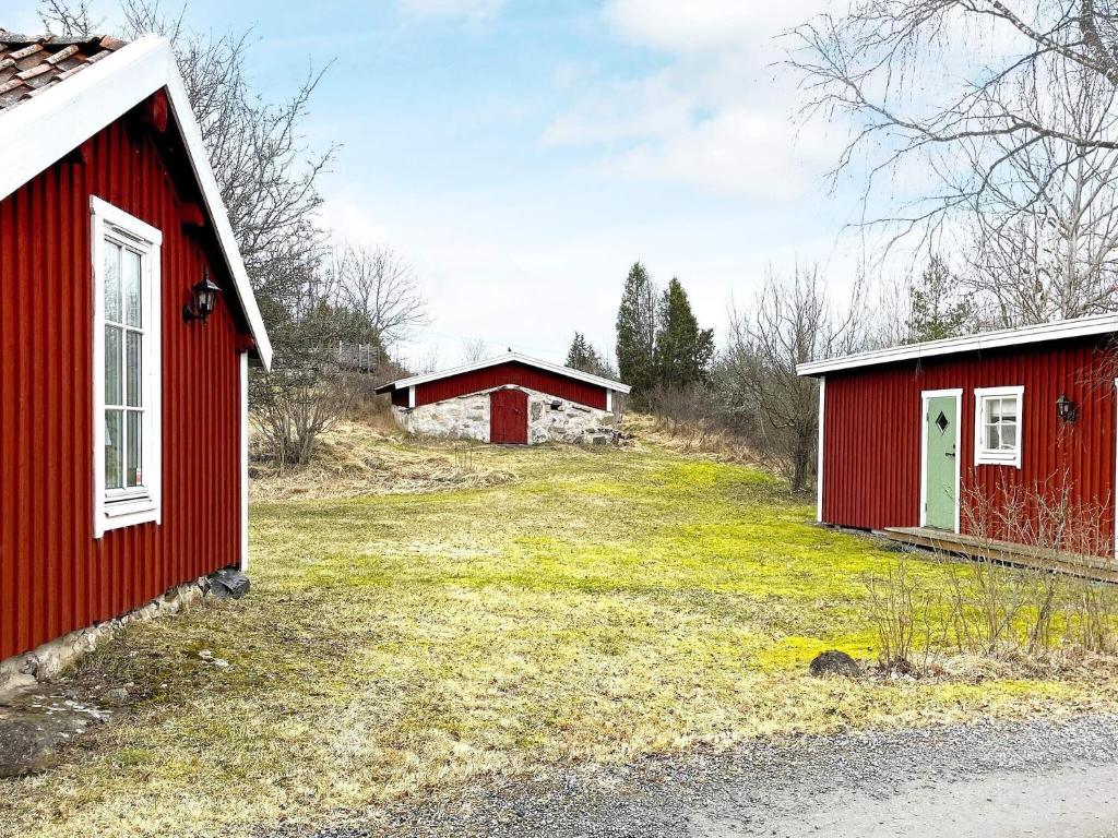 Holiday home VIKBOLANDET III في Arkösund: مبنيان حمران في حقل بجوار الطريق