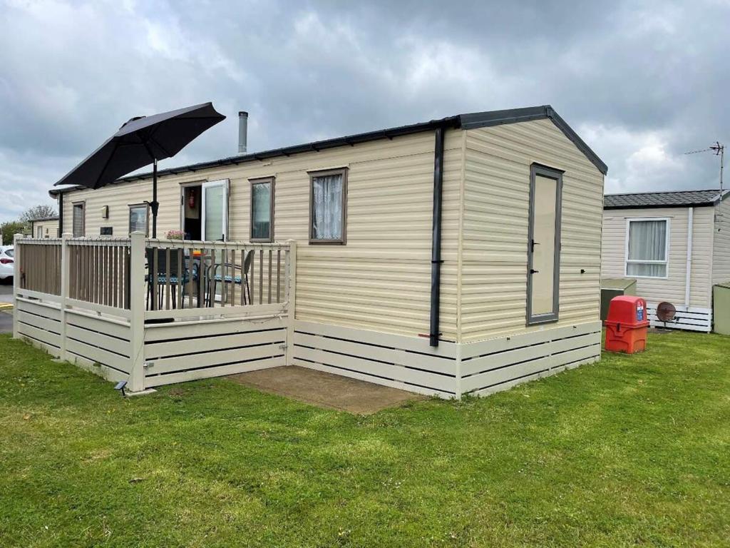 a small house with a deck with an umbrella at 23 The Lawns Pevensey Bay Holiday Park in Pevensey