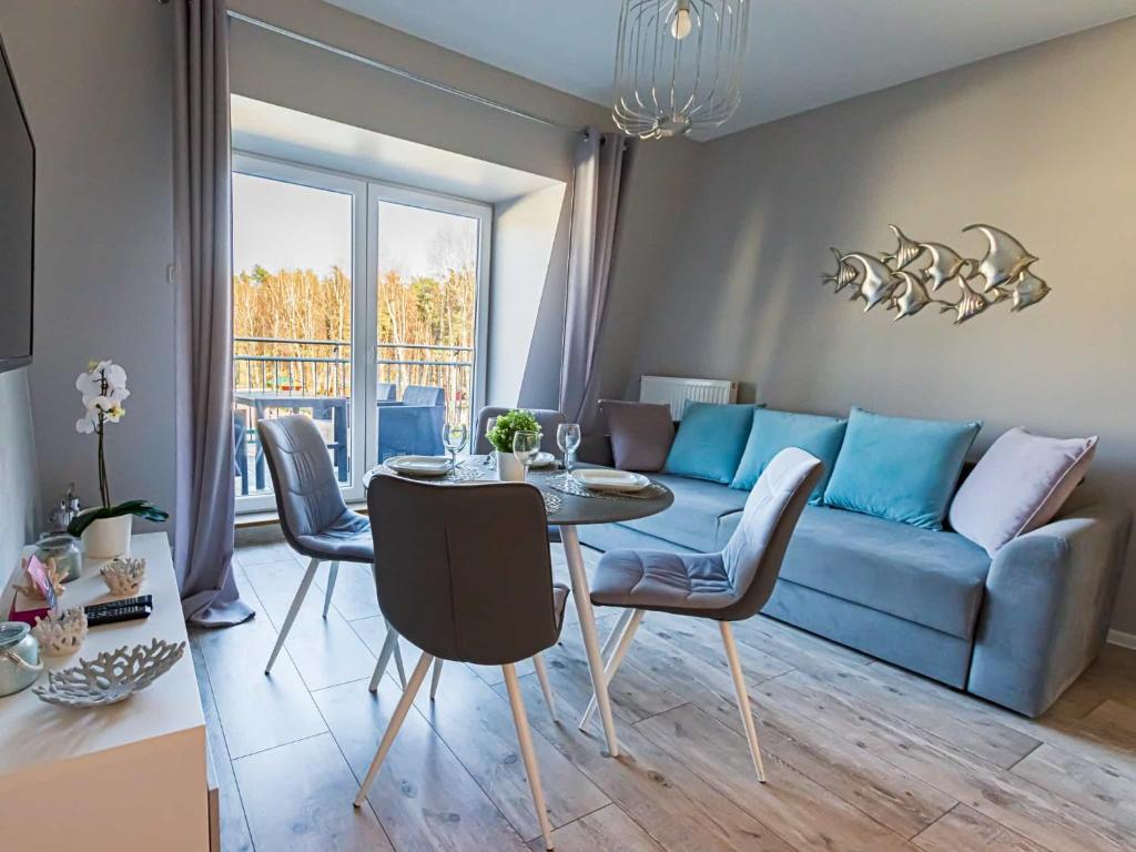a living room with a blue couch and a table at VacationClub - Leśna 12A Apartament 25 in Pobierowo