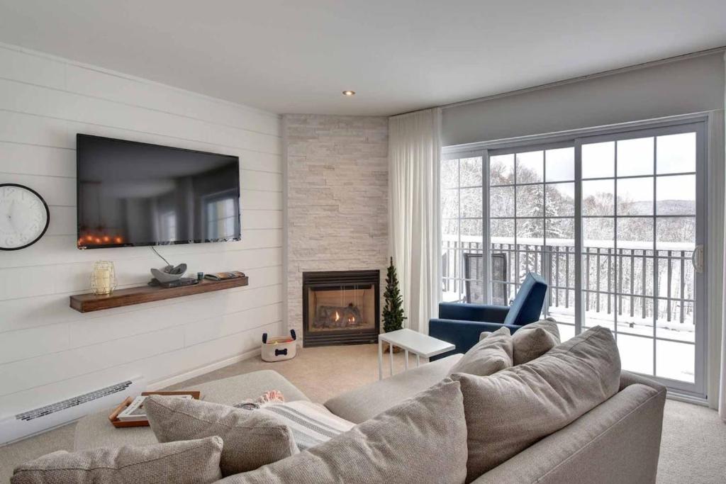 a living room with a couch and a fireplace at Mont-Blanc Ski In Ski Out and Beach in Saint-Faustin