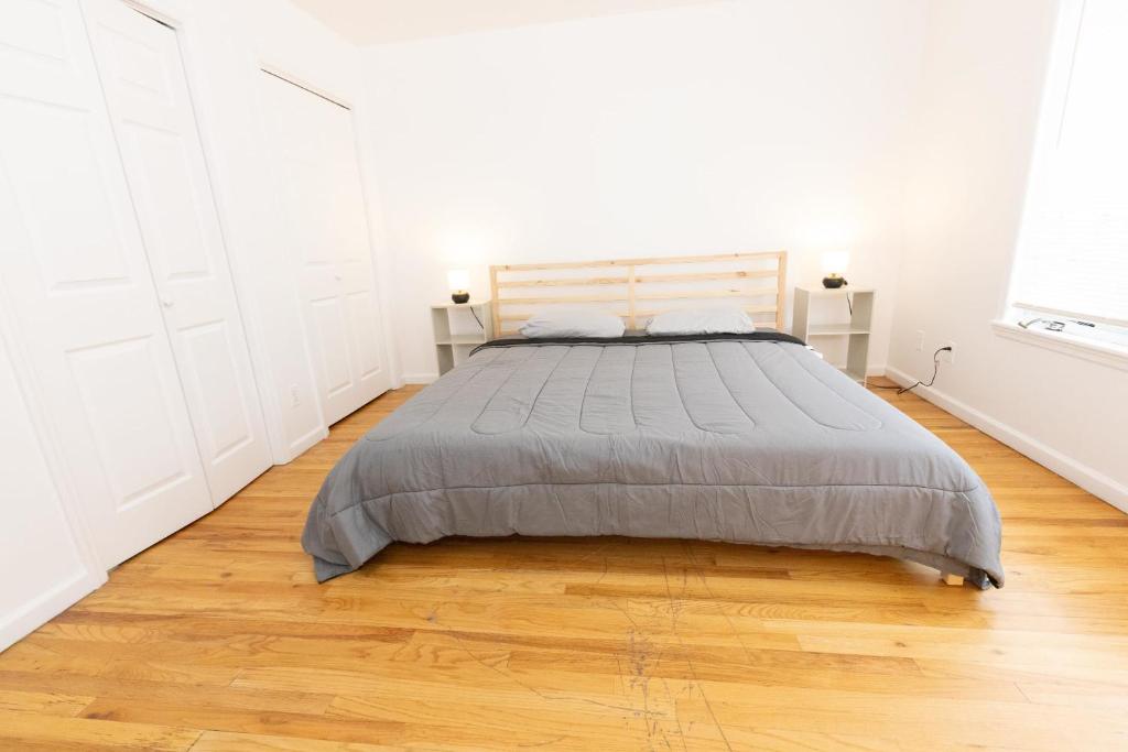 Łóżko w białej sypialni z drewnianą podłogą w obiekcie Stylish & Spacious 3-bed Apt mins to NYC w mieście Jersey City