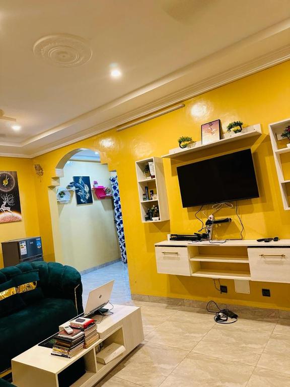 a living room with a yellow wall with a tv at Passion Housse in Ouagadougou