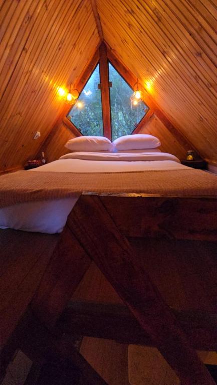 uma cama num quarto de madeira com uma janela em Chalés Araucária - Jacuzzi e Ar Cond - 1h30 de SP em Extrema