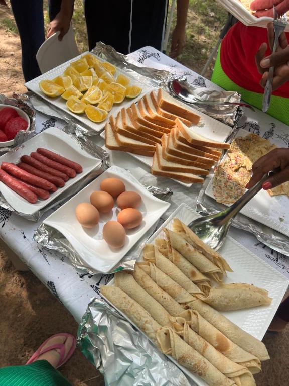 a table topped with hot dogs and eggs and bread at Amarula Tree Hotel Mikumi in Mikumi