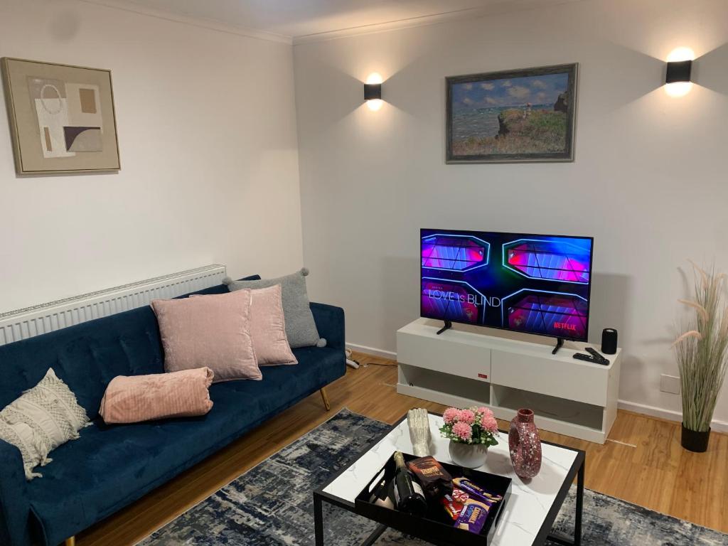uma sala de estar com um sofá azul e uma televisão em New Modern house in Reading with free parking em Caversham