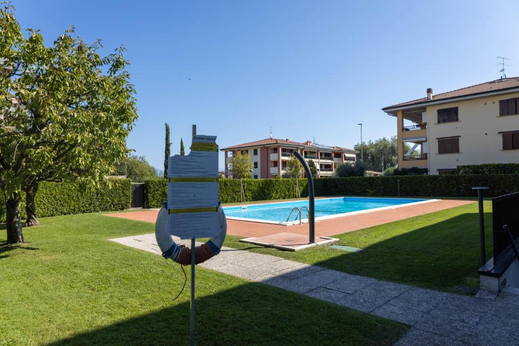 a sign in a yard next to a swimming pool at Patty14 By Case al Lago in Sirmione