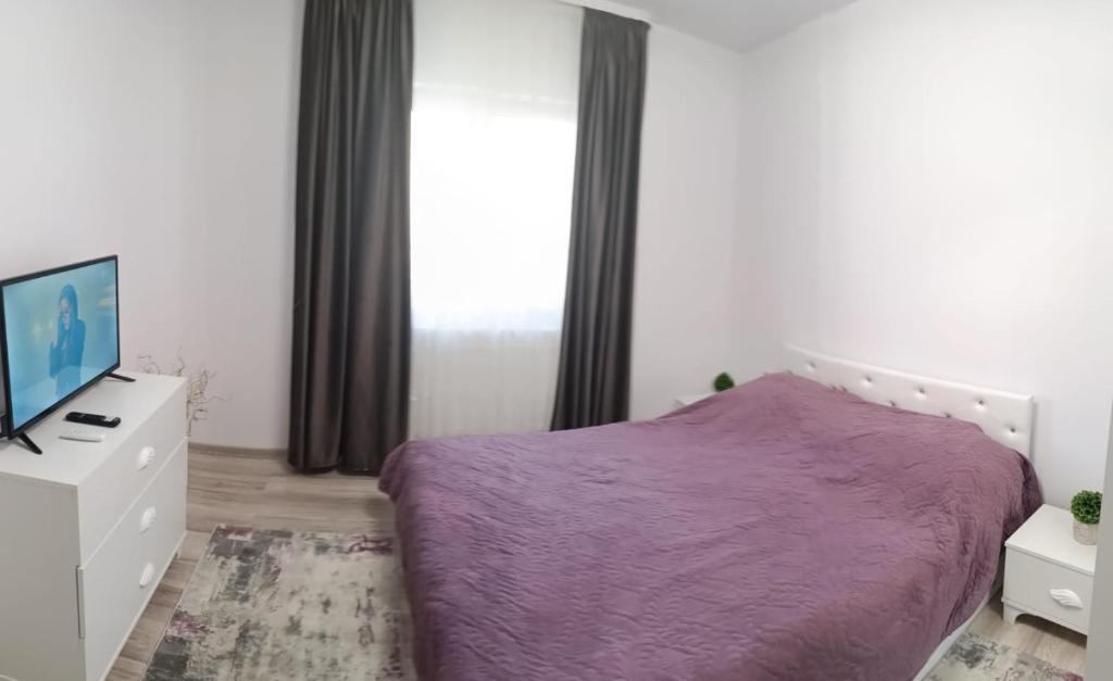 a bedroom with a purple bed and a tv at Piano Apartament in Gura Humorului
