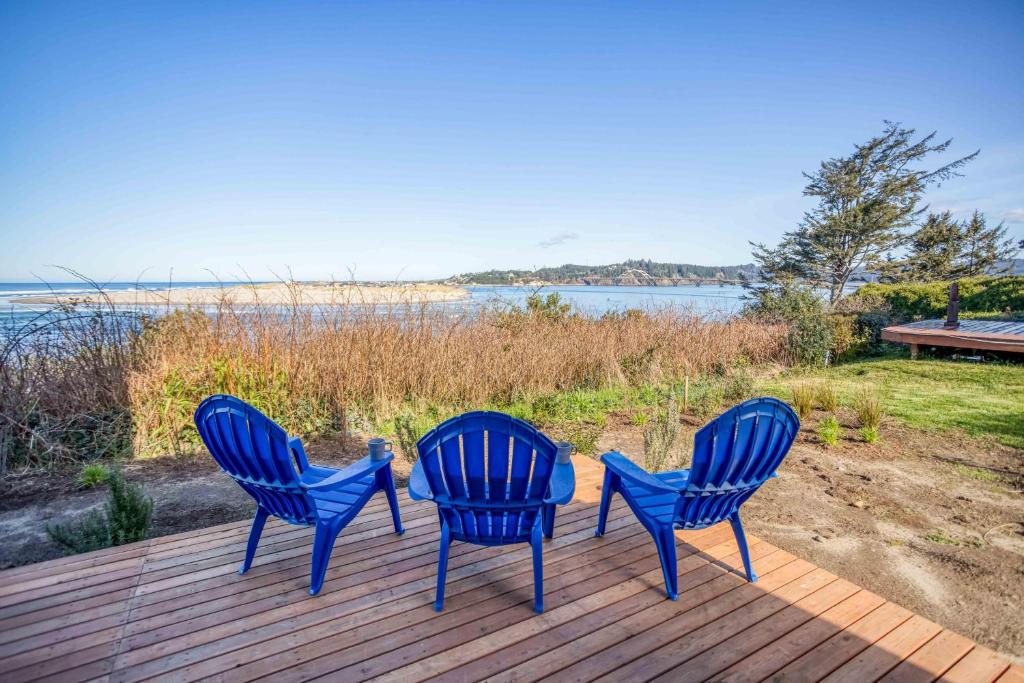 three blue chairs sitting on a deck overlooking the water at Walters Waldport in Waldport