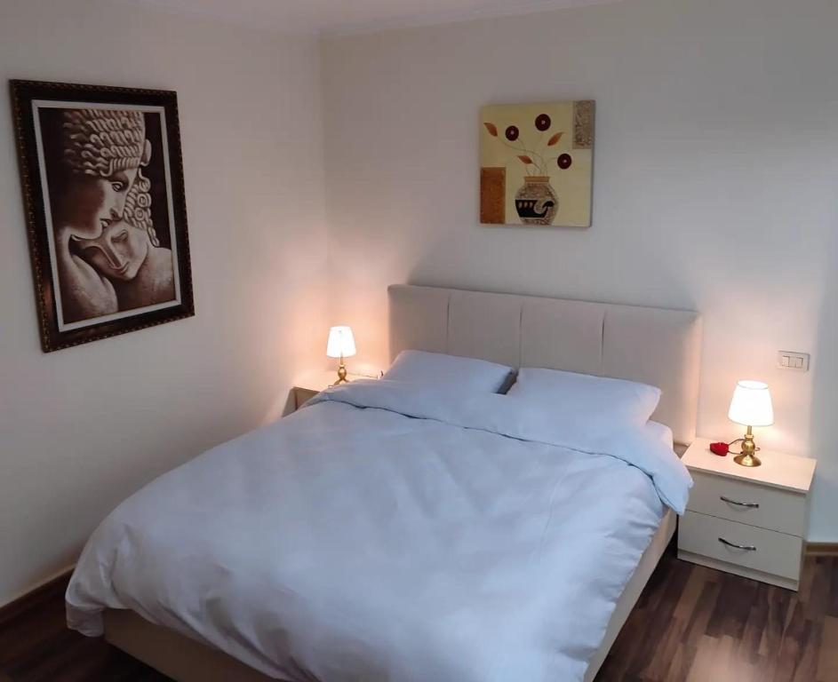 a bedroom with a white bed and two night stands at LB Apartments in Tirana