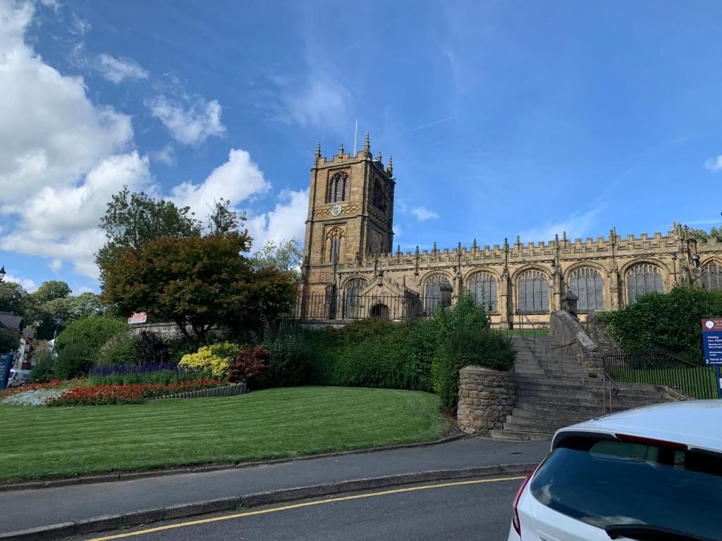 a church with a clock tower and a car parked in front at Town Centre Apartment in Mold