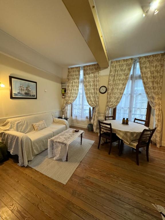 une chambre avec un lit, une table et des fenêtres dans l'établissement la campagne en ville, à Dieppe