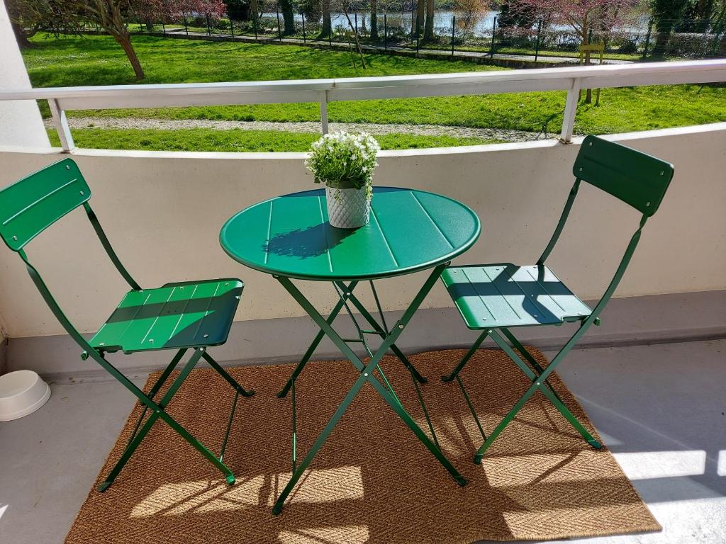 2 chaises et une table avec un vase de fleurs sur le balcon dans l'établissement Appartement Rennes stade, à Rennes