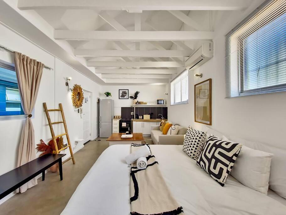 een woonkamer met een witte bank en een tafel bij Unique Studio Close to Promenade in Kaapstad