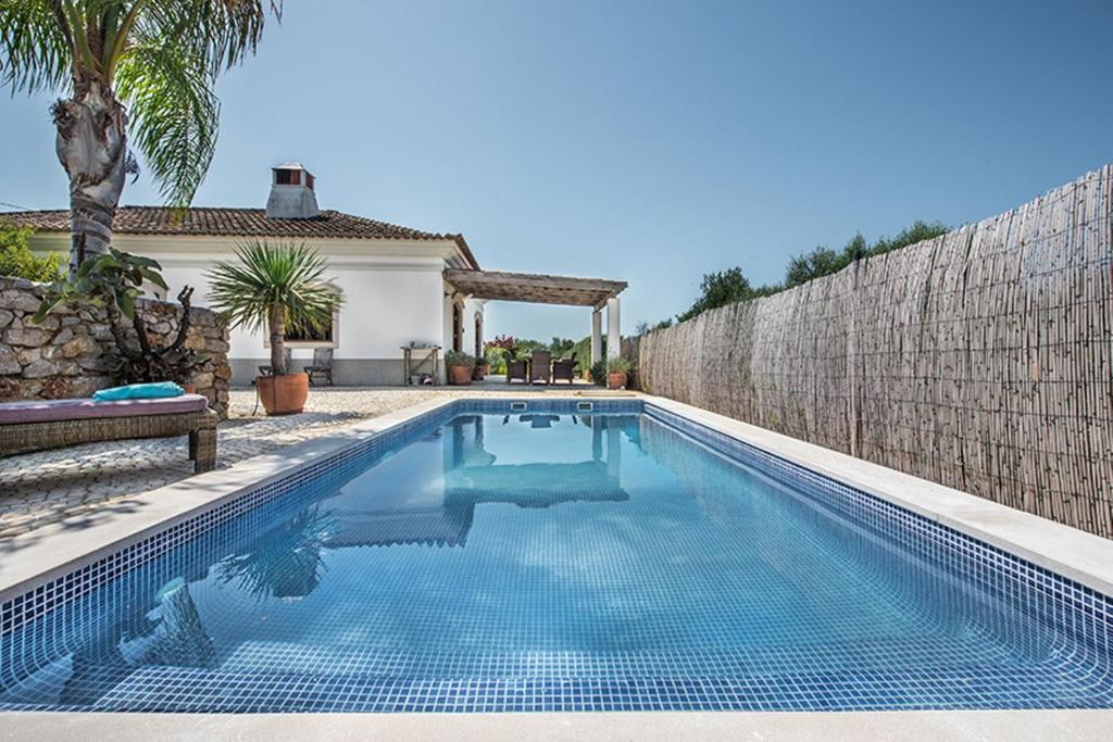 uma piscina em frente a uma casa com uma parede em Casa da Terra Branca em Vila Nova de Cacela