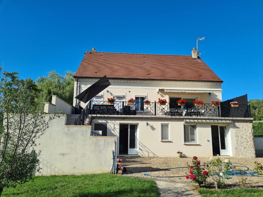 a white house with red flowers on the balcony at Chez Jaja et Phiphi in Bourg-et-Comin