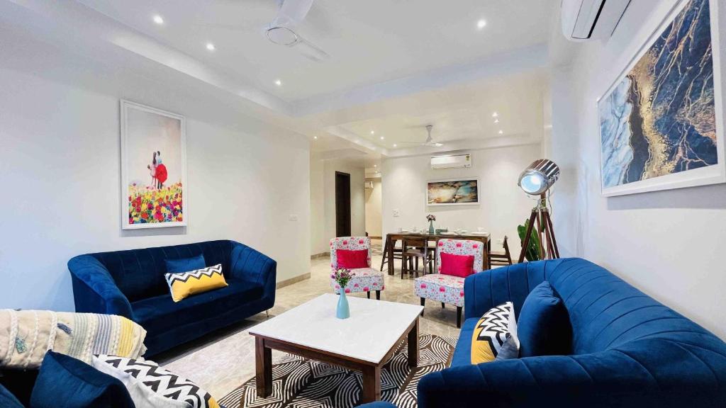 una sala de estar con sofás azules y una mesa. en BluO 3BHK CityWalk Mall, MAX Saket -Lift, Balcony., en Nueva Delhi