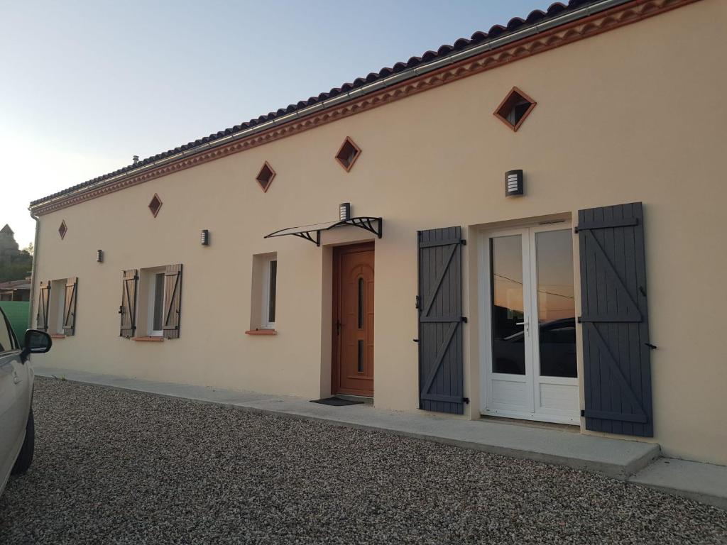 un bâtiment avec des portes et une voiture garée devant dans l'établissement Appartement spacieux et confortable à Clermont-Dessous, terrasse, à Clermont-Dessous