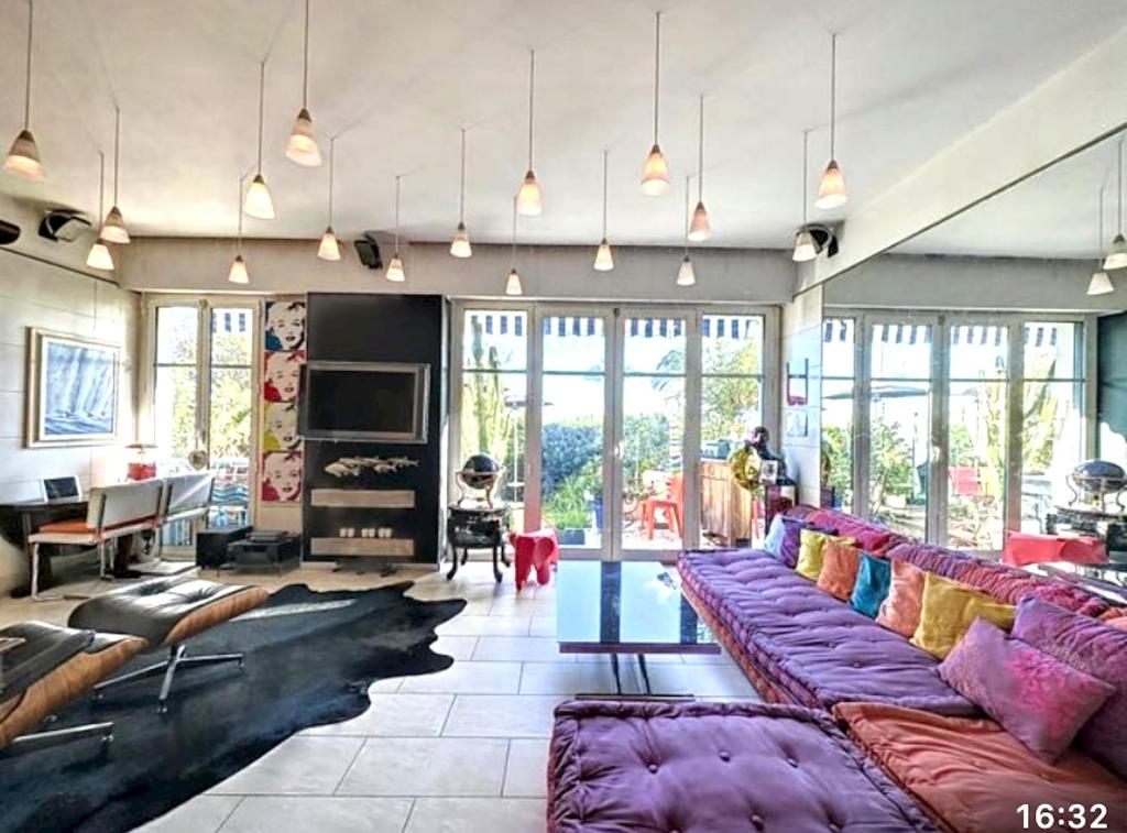 - un grand salon avec des canapés violets et une table dans l'établissement Appartement charmant en bord de mer à Nice 60 m² avec terrasse privée, à Nice