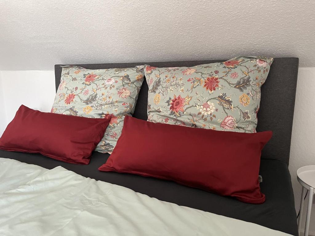 een bed met 3 kussens en 2 rode kussens bij Zur Stadtmama in Endingen