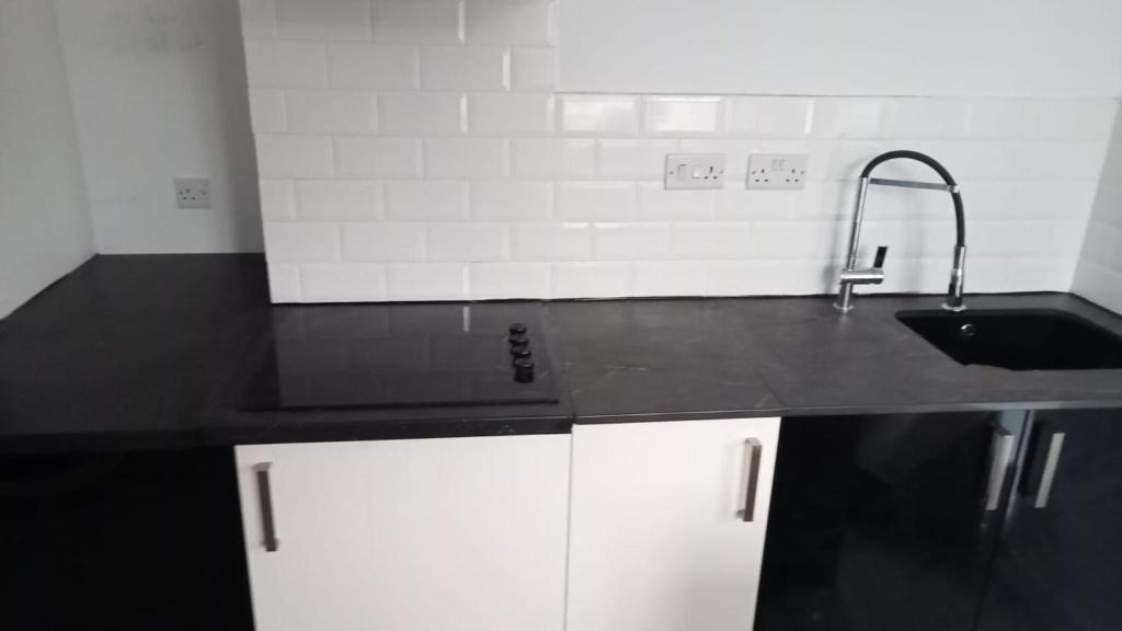 a kitchen with a sink and a black counter top at Bike Park 5 miles2-Bed cottage in Merthyr Vale in Merthyr Tydfil