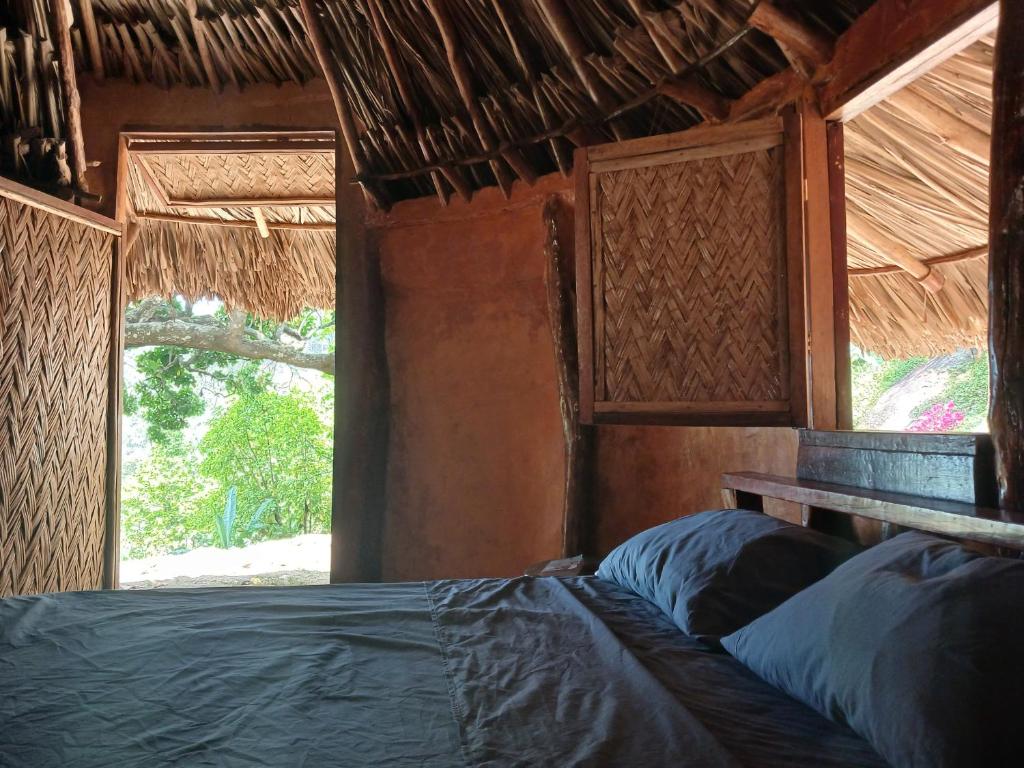 a bed in a room with a window at Private waterfall and indigenous house! in Minca