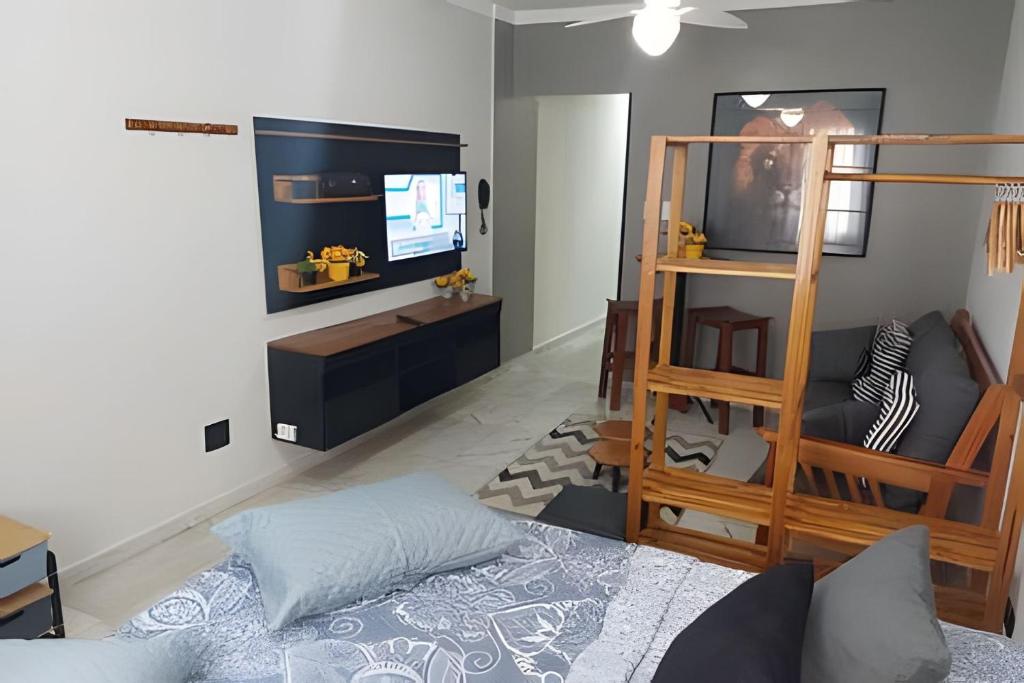 Una sala de estar con una cama y un televisor. en Em frente ao quiosque Ocian na praia, pé na areia, en Praia Grande
