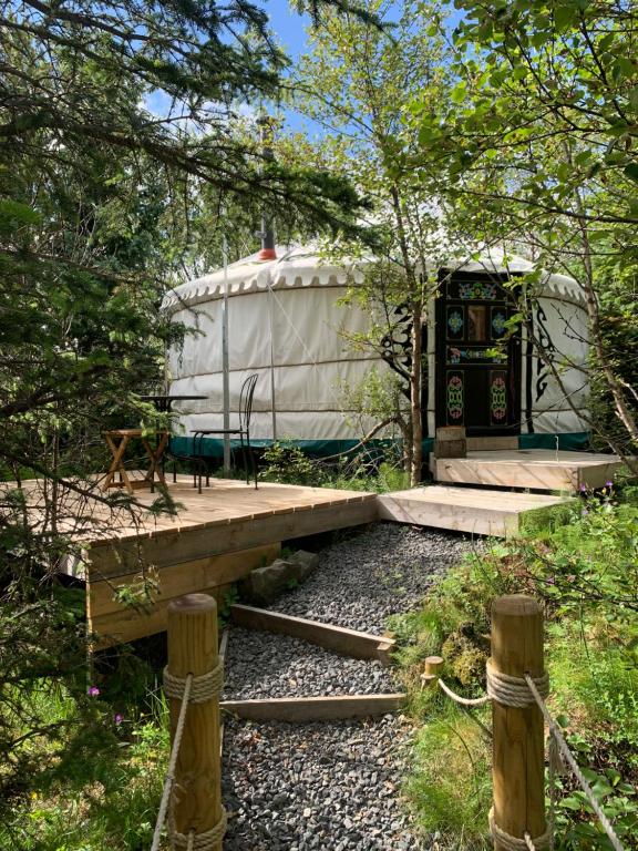 a yurt with a wooden bridge in the woods at Valhalla Yurts Freya in Selfoss