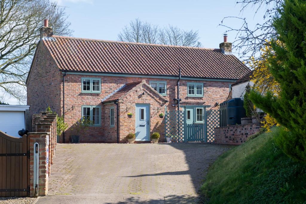 ein Backsteinhaus mit einer blauen Tür und einer Einfahrt in der Unterkunft 5* Family Holiday Home in the Yorkshire Wolds in Huggate