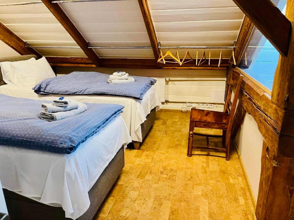 two beds in a room with a chair and a window at LOSSI 21/23 in Tartu