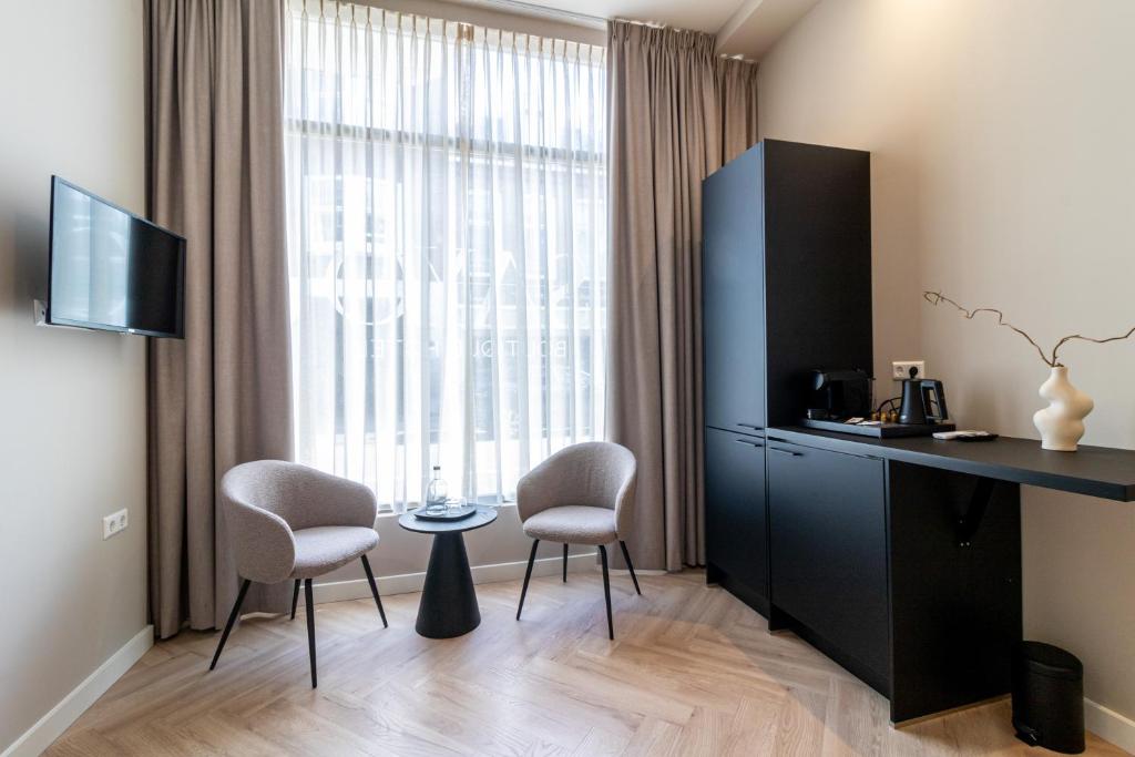 een kamer met een bureau, 2 stoelen en een raam bij SAYŌ Boutique Hotel in Scheveningen