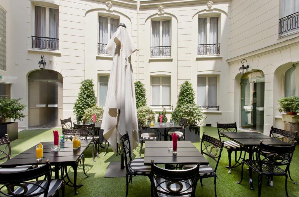 a patio with tables and chairs and a umbrella at Elysees Apartments in Paris