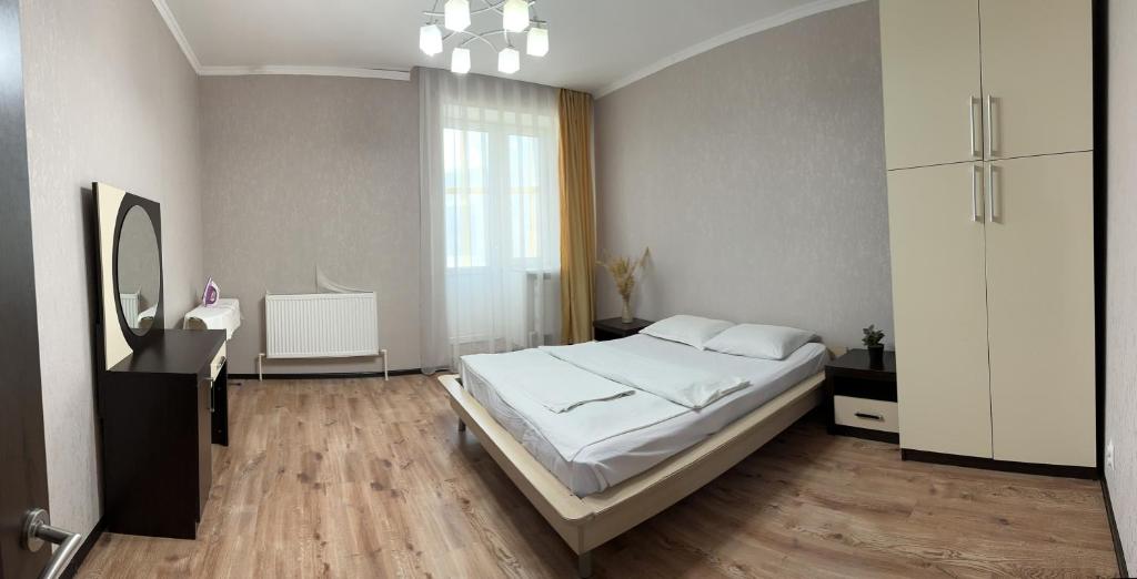 a bedroom with a white bed and a mirror at Уютная рядом с парком in Uralsk