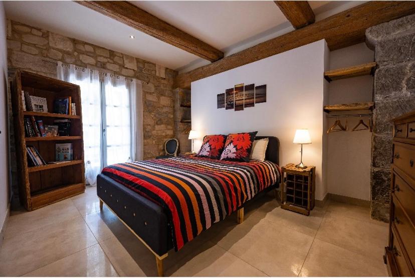 - une chambre avec un grand lit et un mur en pierre dans l'établissement Pietra Viva, à Les Matelles