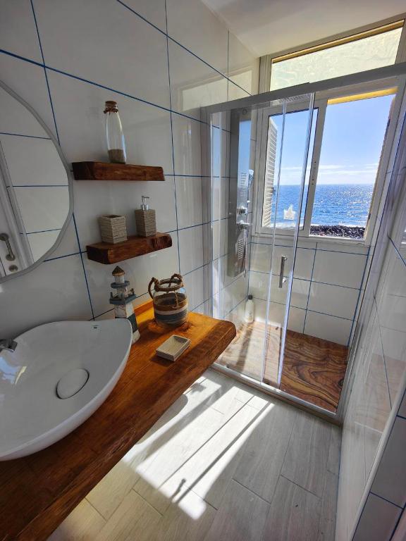 a bathroom with a sink and a shower with a window at Vacacional Sunbeach Candelaria in Candelaria