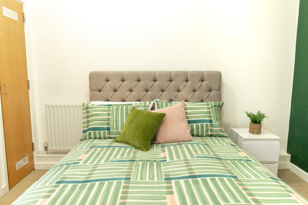 a bedroom with a bed with green and pink pillows at Vibrant Two Bedroom House near Canary Wharf in London
