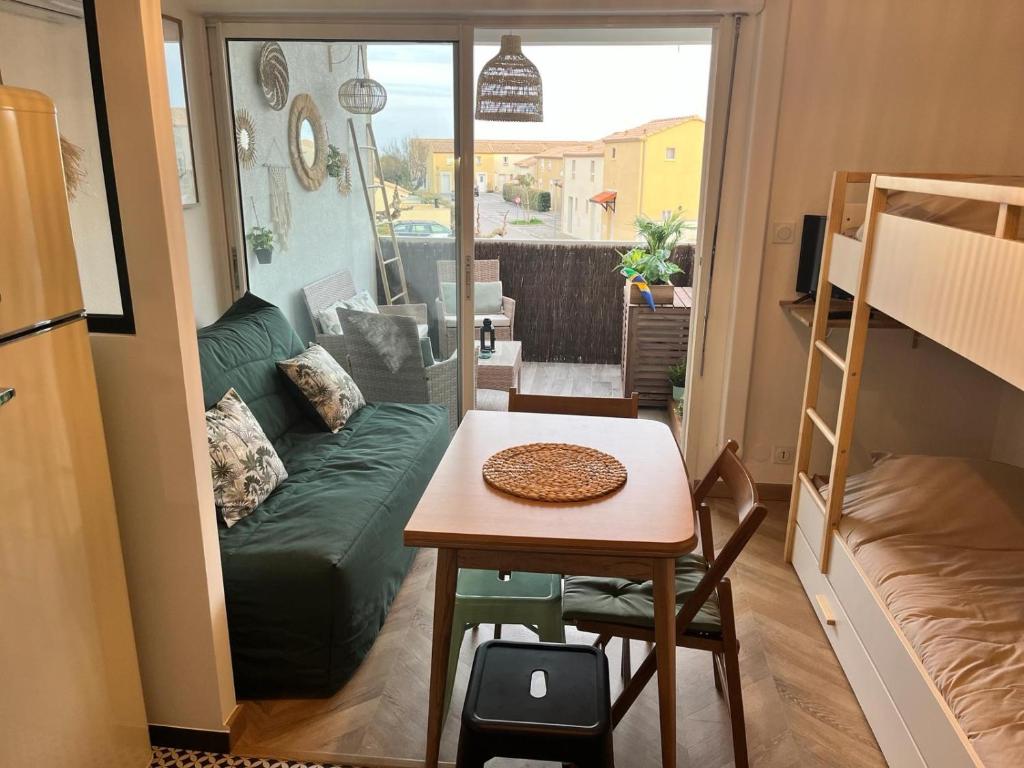 a small room with a table and a couch at Tropical Duplex : Bord de mer + Piscine in Frontignan