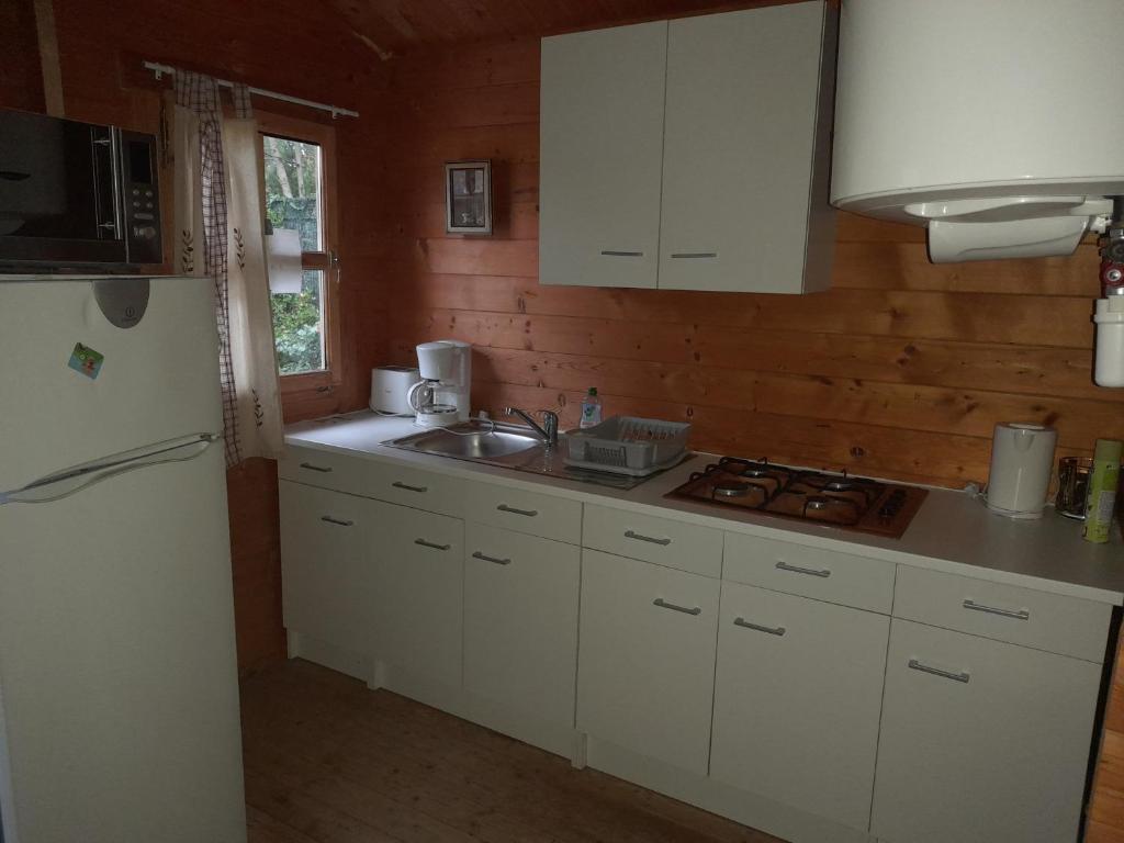 La cuisine est équipée de placards blancs, d'un évier et d'un réfrigérateur. dans l'établissement Val Marie Equitation, à Villeneuve-de-la-Raho