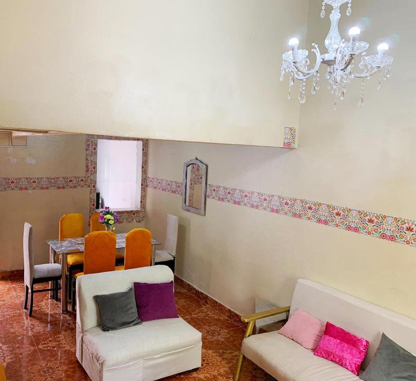 ein Wohnzimmer mit einem Tisch, Stühlen und einem Kronleuchter in der Unterkunft Alojamiento a 6 cuadras de la plaza in Cusco
