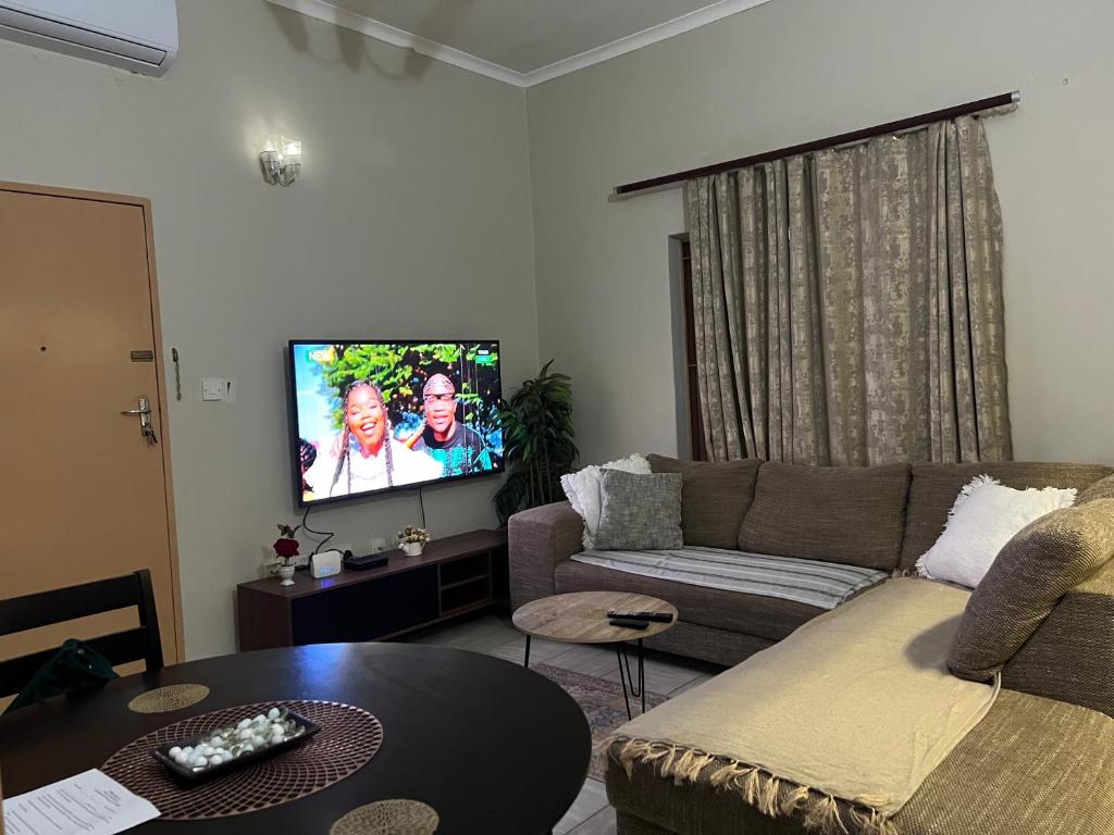 a living room with a couch and a flat screen tv at Brilliant Home in Gaborone