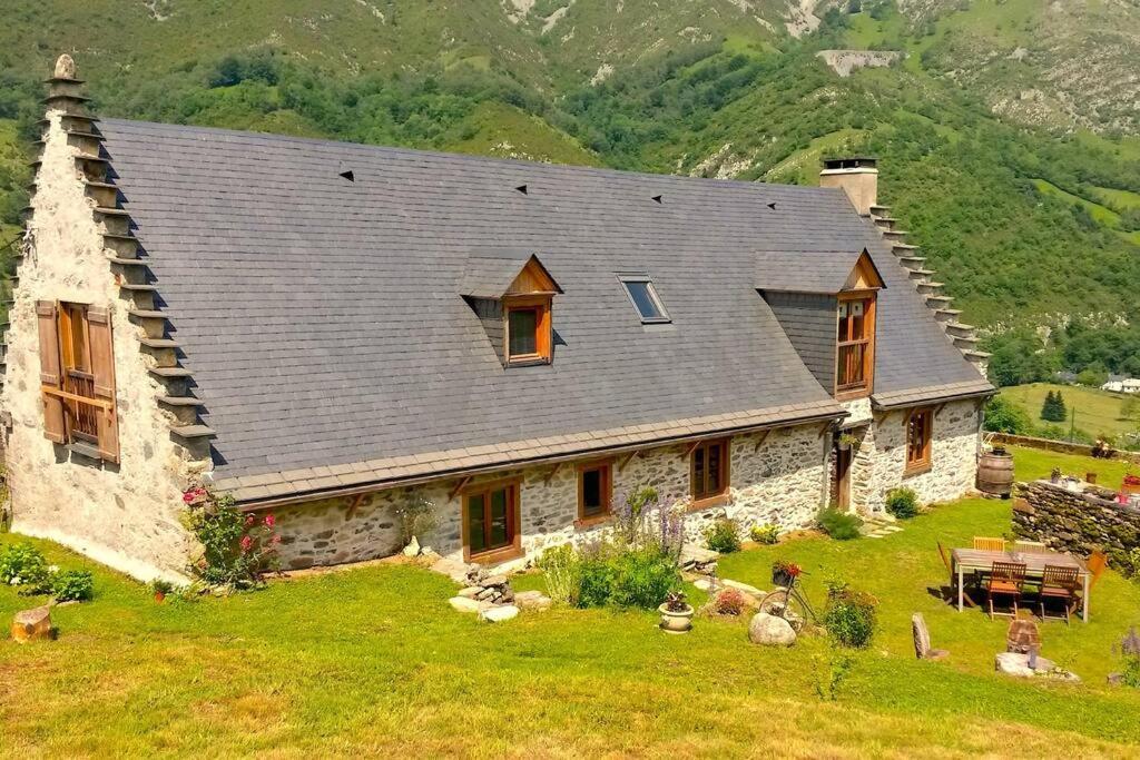 une grande maison en pierre avec un toit sur un champ dans l'établissement La Grange de Gassiole, à Campan