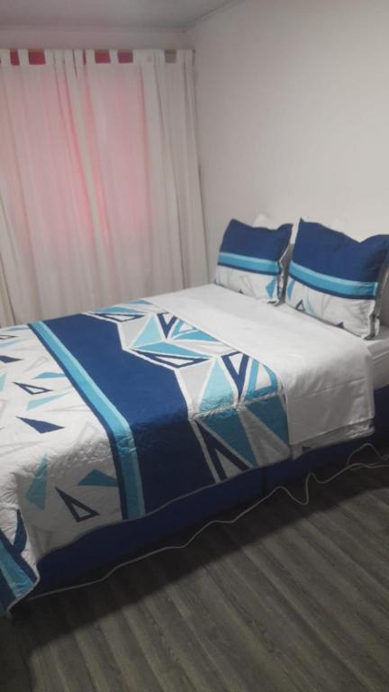 a bed with a blue and white comforter in a room at el descanso 2 in Bogotá
