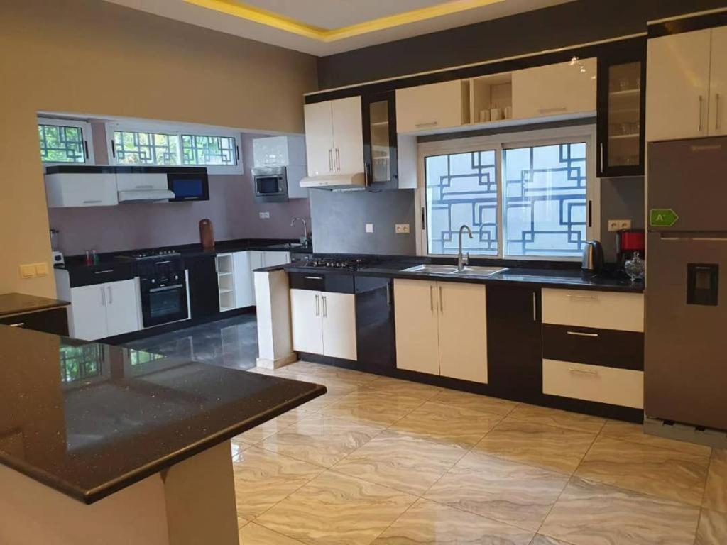 a large kitchen with white cabinets and a sink at Paradis des anges in Yaoundé