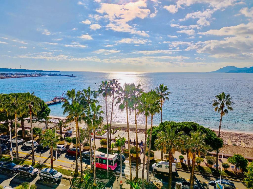 a view of a beach with palm trees and the ocean at Incroyables appartements dans une résidence de haut standing in Cannes