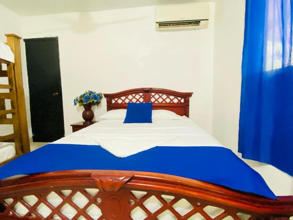 um quarto com uma cama com uma almofada azul em HOSTAL OLAS CLUB DE NEGUANJE -TAYRONA em Santa Marta