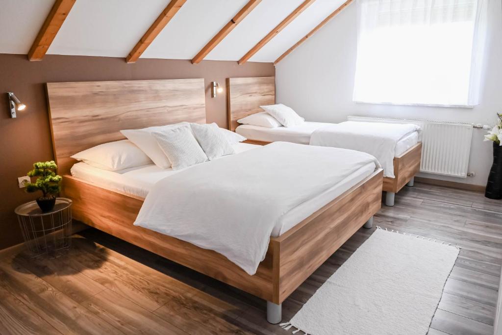 two beds in a bedroom with wooden floors at Guesthouse Rubcic in Rakovica
